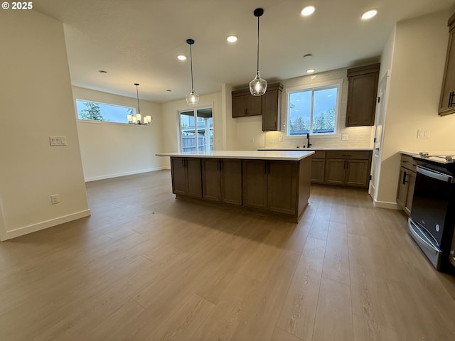 kitchen featuring a center island, range with electric cooktop, decorative light fixtures, light hardwood / wood-style floors, and decorative backsplash