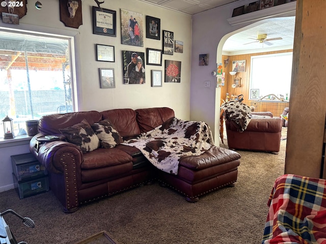 living area featuring carpet flooring, healthy amount of natural light, arched walkways, and ceiling fan