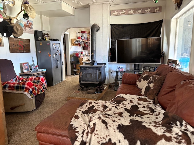 carpeted living room with arched walkways and a wood stove
