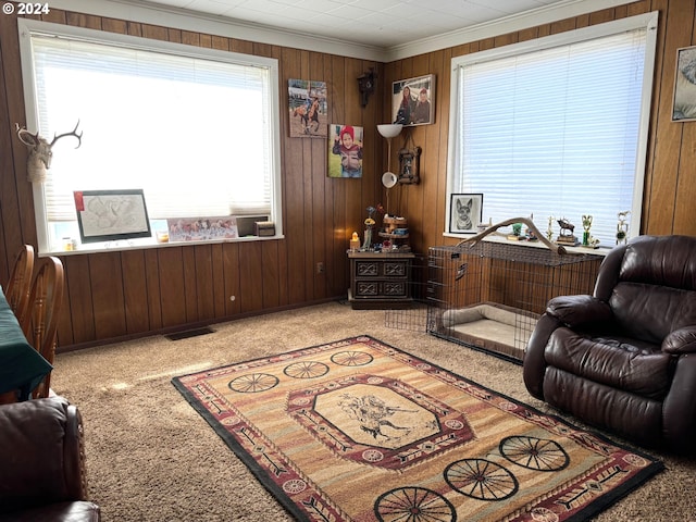 sitting room featuring carpet floors, wood walls, and ornamental molding