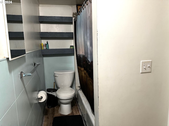 bathroom featuring toilet, a shower with shower curtain, and wood finished floors