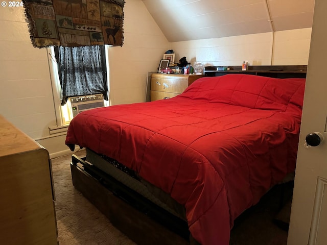 carpeted bedroom with vaulted ceiling and concrete block wall