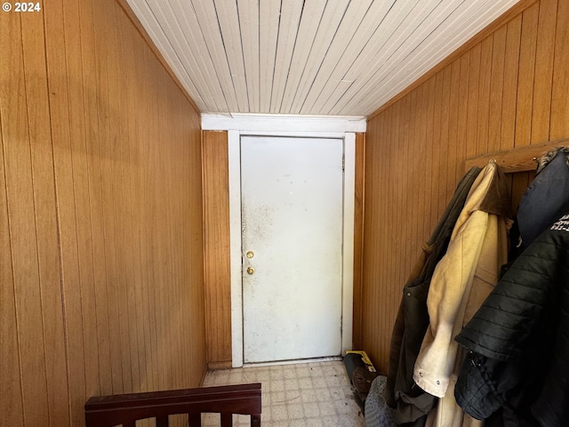 doorway featuring light flooring, wooden walls, and wooden ceiling