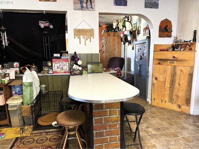 kitchen with a kitchen breakfast bar, arched walkways, light countertops, and a peninsula