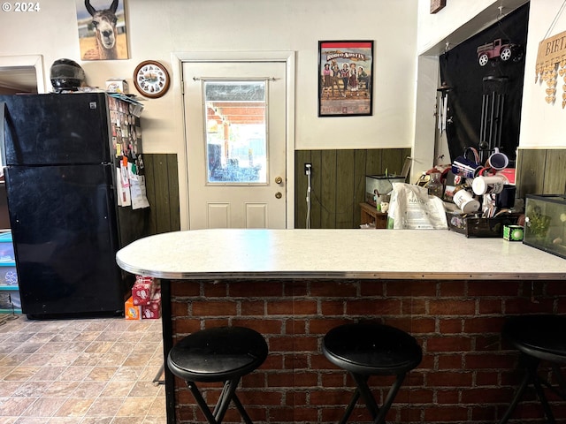 kitchen featuring a kitchen breakfast bar and black refrigerator