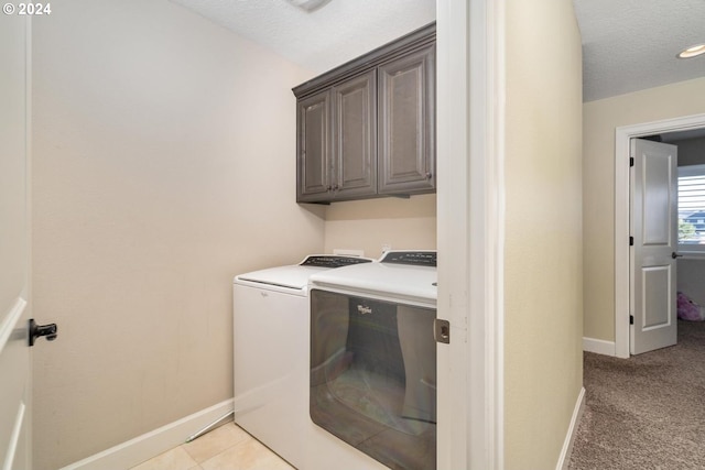 washroom with a textured ceiling, light carpet, washing machine and clothes dryer, baseboards, and cabinet space
