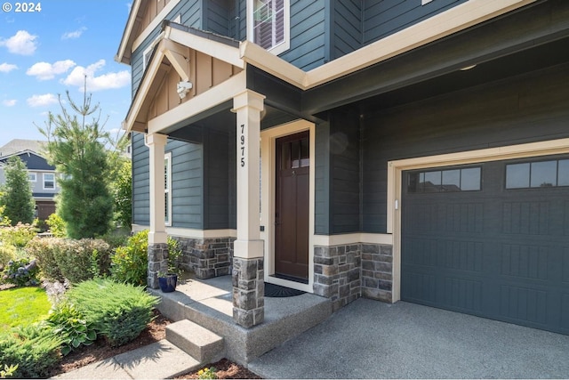 view of exterior entry featuring stone siding, covered porch, and a garage