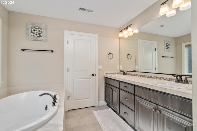 bathroom featuring a garden tub, double vanity, visible vents, and a sink