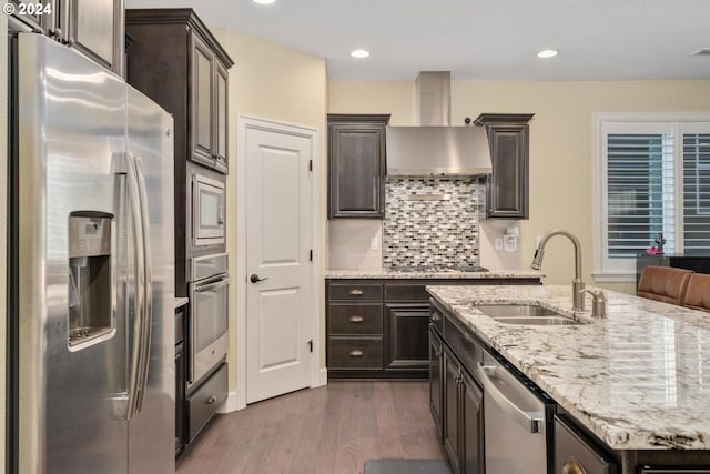 kitchen featuring appliances with stainless steel finishes, sink, dark hardwood / wood-style flooring, dark brown cabinetry, and wall chimney exhaust hood