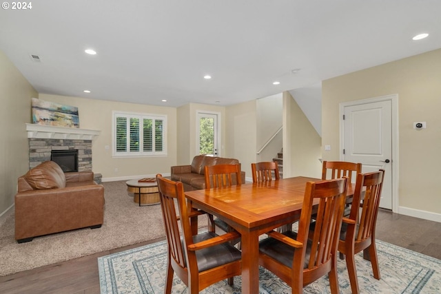 dining area with hardwood / wood-style floors and a stone fireplace