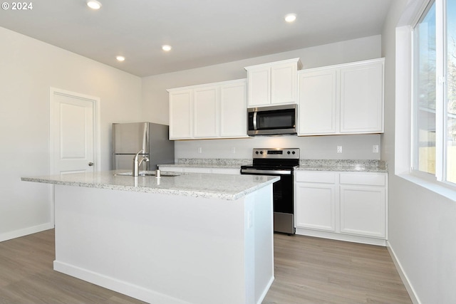 kitchen with sink, white cabinets, a kitchen island with sink, and stainless steel appliances