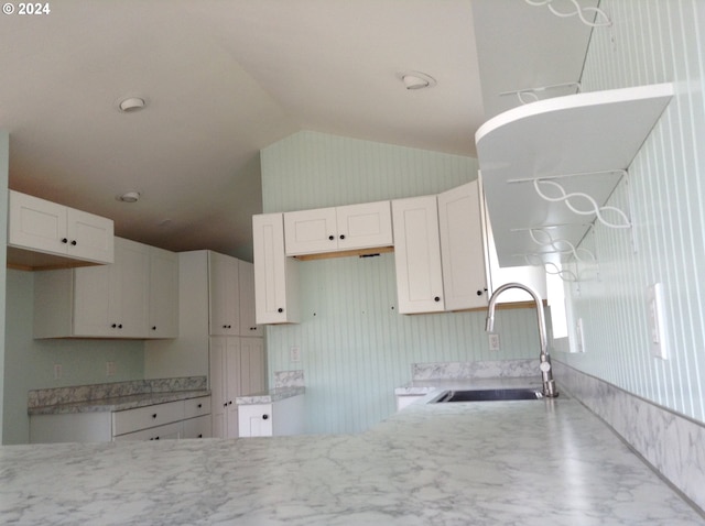 kitchen featuring white cabinetry, sink, and lofted ceiling