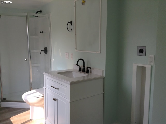 bathroom with vanity, toilet, wood-type flooring, and a shower with shower door