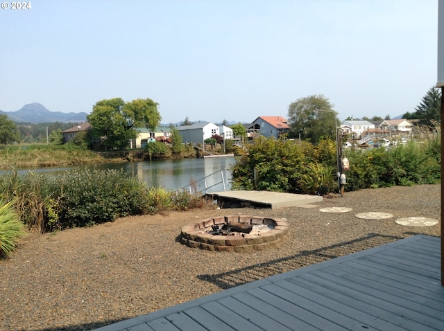 wooden deck featuring a water and mountain view and a fire pit