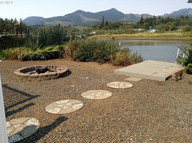 view of yard with a water and mountain view and an outdoor fire pit