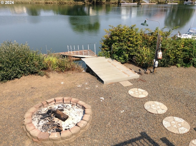 view of dock with a fire pit and a water view