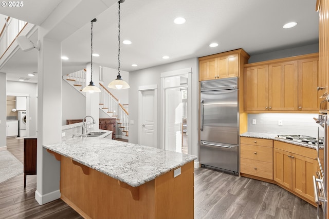 kitchen featuring kitchen peninsula, appliances with stainless steel finishes, dark hardwood / wood-style flooring, and decorative light fixtures