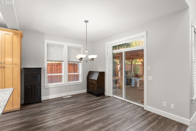 unfurnished dining area with dark hardwood / wood-style flooring and a notable chandelier