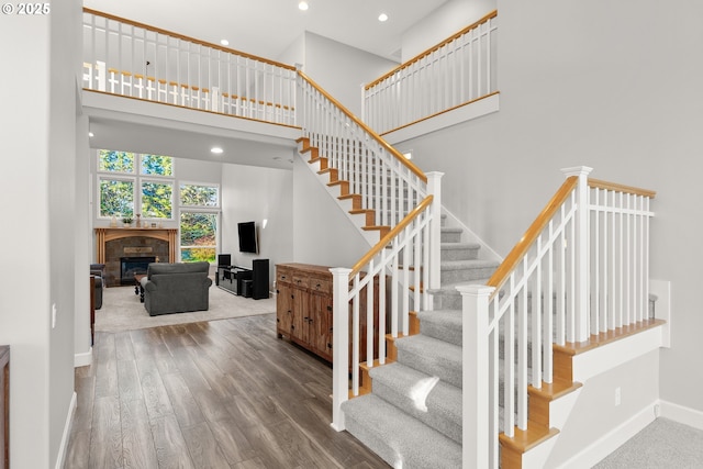 stairs with hardwood / wood-style floors and a high ceiling