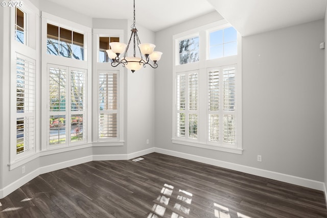 unfurnished dining area featuring plenty of natural light, dark hardwood / wood-style floors, and a notable chandelier