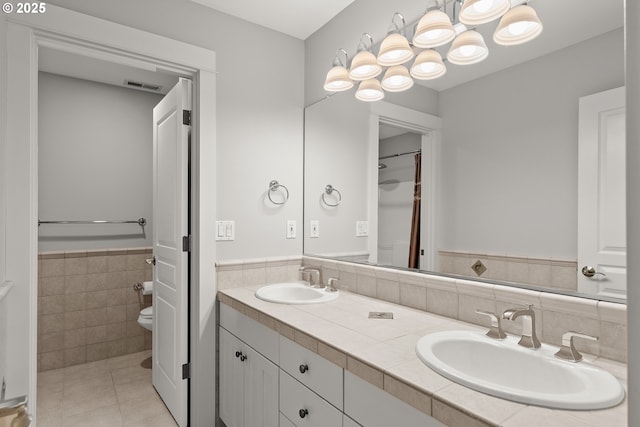 bathroom with tile patterned floors, vanity, tile walls, and toilet