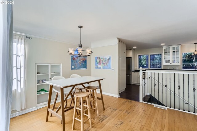 dining area with light hardwood / wood-style floors, a healthy amount of sunlight, and a chandelier