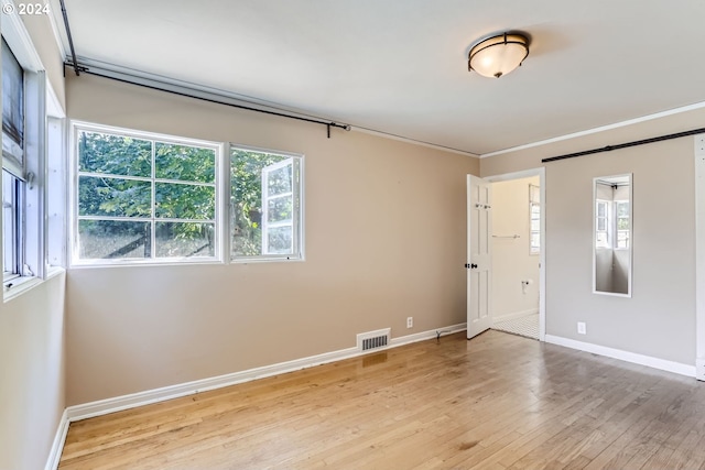 empty room with light hardwood / wood-style floors and ornamental molding