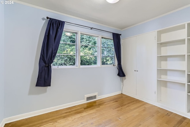 unfurnished bedroom featuring light wood-type flooring, visible vents, ornamental molding, and baseboards