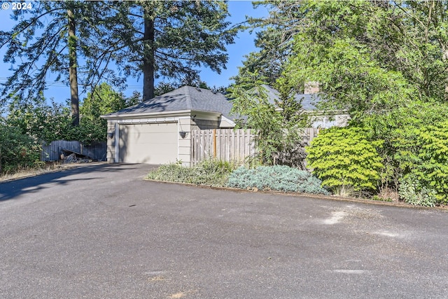 view of home's exterior with a detached garage and fence