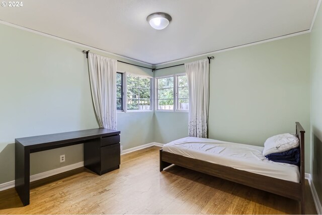 bedroom featuring light wood-type flooring and crown molding