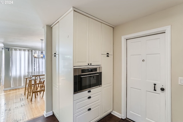 kitchen featuring dark hardwood / wood-style flooring, oven, and white cabinets