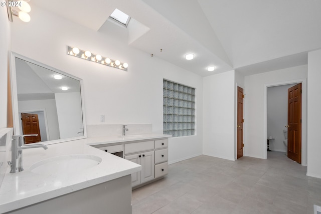 bathroom featuring vanity, vaulted ceiling with skylight, toilet, and tile patterned floors