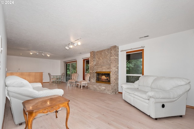 living room with a textured ceiling, light hardwood / wood-style floors, and a fireplace