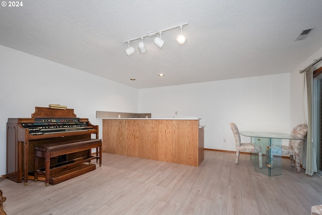 misc room featuring a textured ceiling, light hardwood / wood-style flooring, and track lighting