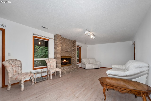 living room with a textured ceiling, light hardwood / wood-style floors, and a fireplace