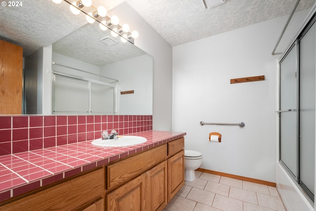 bathroom featuring toilet, tile patterned flooring, vanity, a textured ceiling, and decorative backsplash