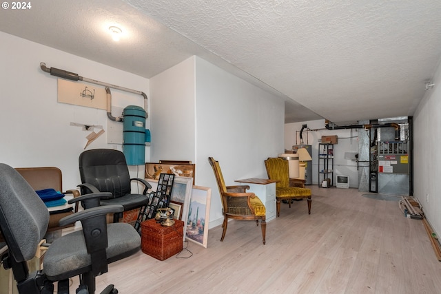 office with heating unit, a textured ceiling, and light hardwood / wood-style flooring