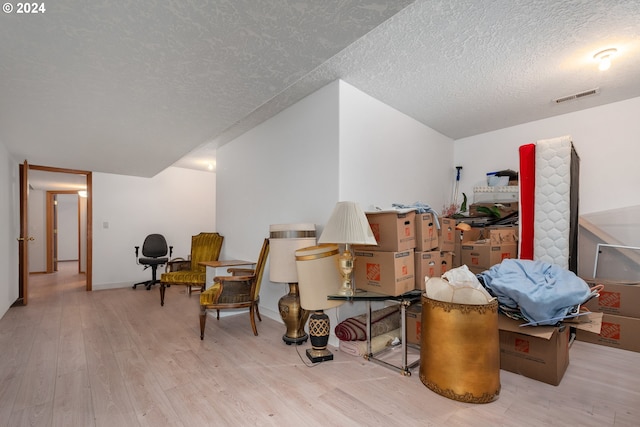 additional living space featuring a textured ceiling and light hardwood / wood-style flooring