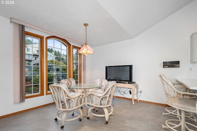 dining room featuring a textured ceiling, vaulted ceiling, and concrete floors