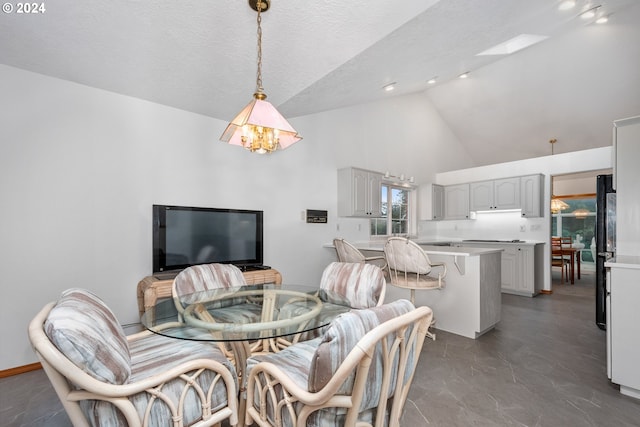 dining space with a textured ceiling, high vaulted ceiling, and a notable chandelier