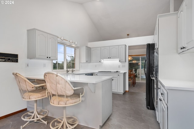 kitchen featuring a breakfast bar, kitchen peninsula, and high vaulted ceiling