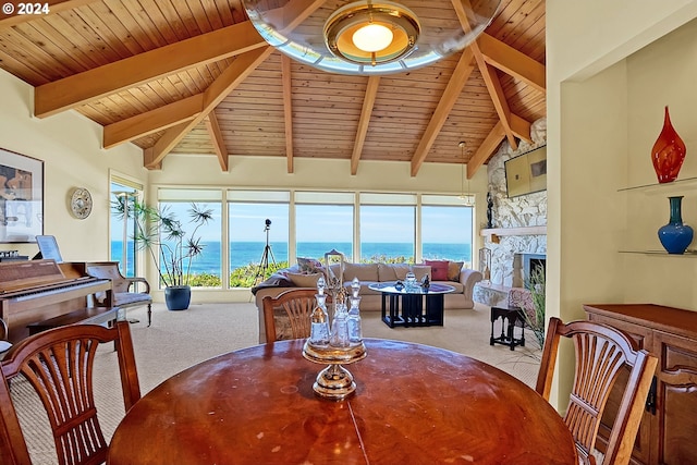 dining area with a stone fireplace, lofted ceiling with beams, wooden ceiling, and light carpet