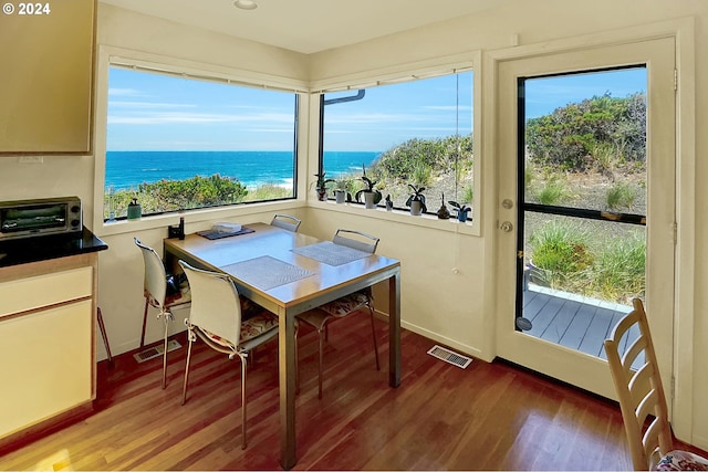 dining room featuring visible vents, a water view, wood finished floors, and a toaster