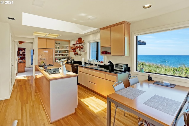 kitchen featuring light brown cabinetry, open shelves, a sink, a center island, and light wood-style floors