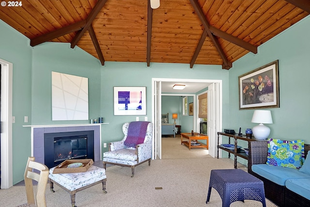 living area with vaulted ceiling with beams, wooden ceiling, carpet flooring, and a tiled fireplace