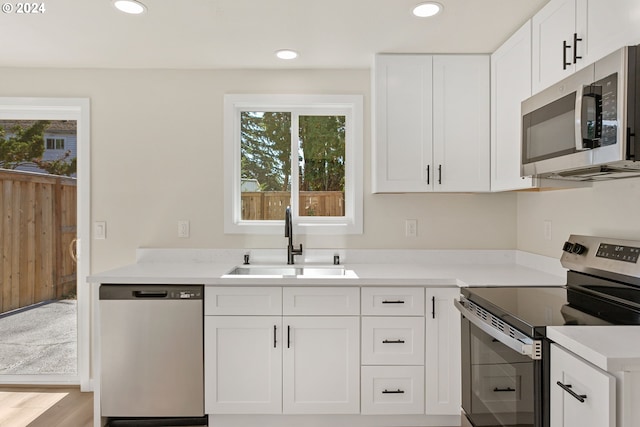 kitchen featuring stainless steel appliances, plenty of natural light, sink, and white cabinetry