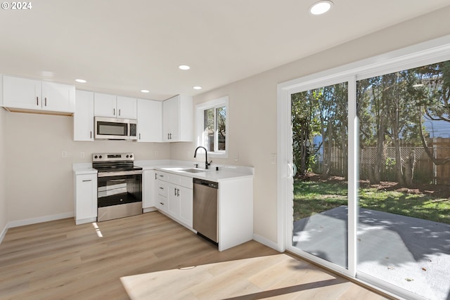 kitchen featuring appliances with stainless steel finishes, light wood-type flooring, sink, and white cabinets