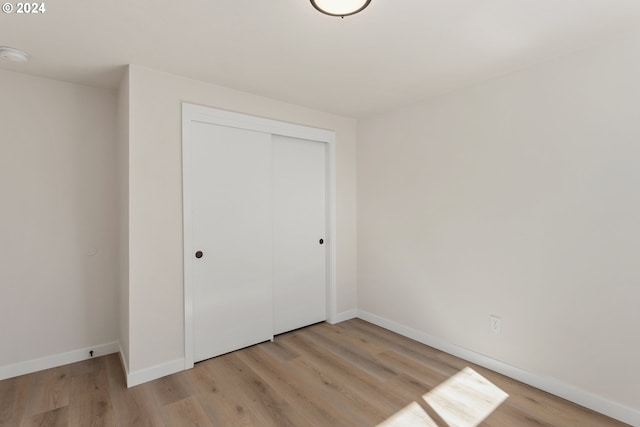 unfurnished bedroom with light hardwood / wood-style flooring and a closet