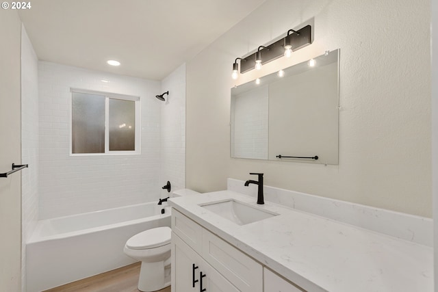 full bathroom featuring wood-type flooring, vanity, tiled shower / bath combo, and toilet