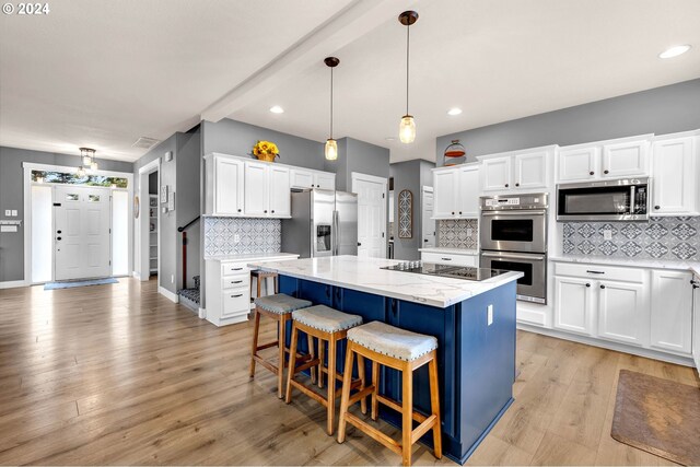 kitchen with hanging light fixtures, white cabinets, tasteful backsplash, a kitchen island, and stainless steel appliances